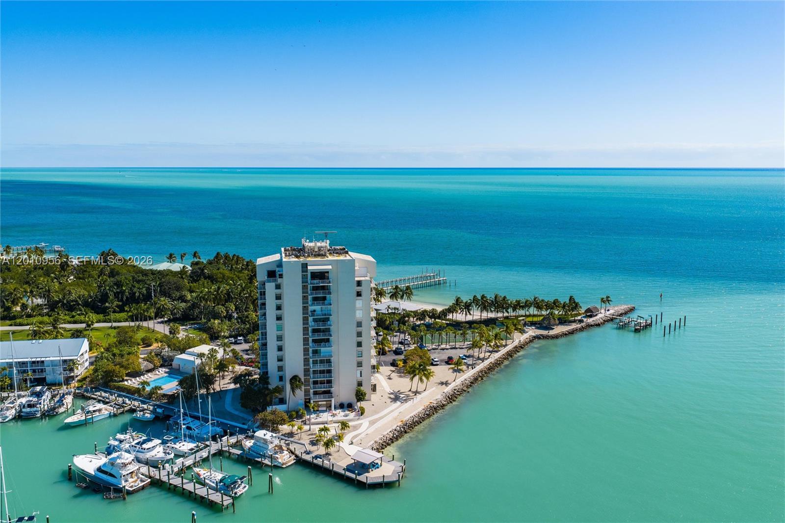 An aerial view shows a tall residential building situated on a point surrounded by water — 2000 Coco Plum Dr # 601, Marathon FL 33050, MARATHON, FL