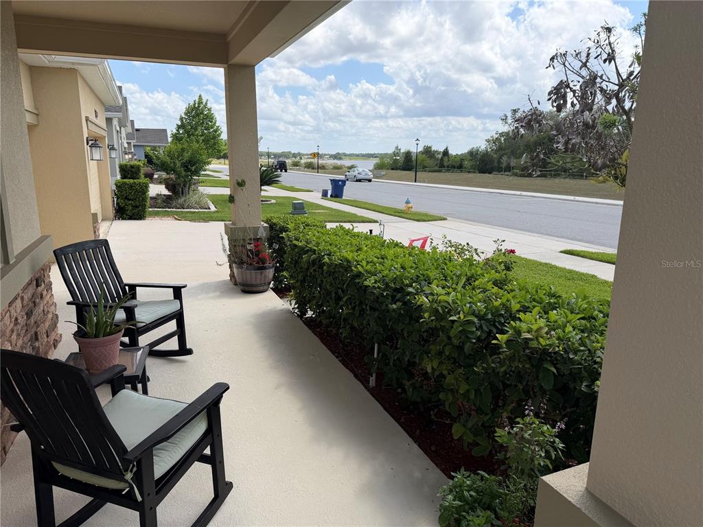 A covered front porch features two rocking chairs and a view of the street — 1927 PERCH HAMMOCK LOOP, GROVELAND, FL