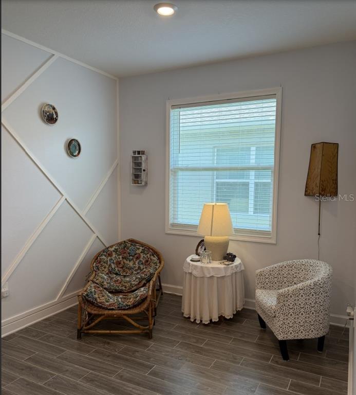 A room with wood-look tile flooring, a geometric accent wall, and two chairs with table — 1927 PERCH HAMMOCK LOOP, GROVELAND, FL