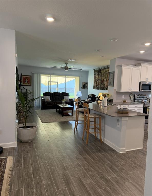 An open-concept living room and kitchen featuring wood-look tile flooring and a breakfast bar — 1927 PERCH HAMMOCK LOOP, GROVELAND, FL