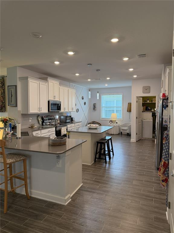 A kitchen with white cabinets, gray countertops, a center island, and wood-look tile flooring — 1927 PERCH HAMMOCK LOOP, GROVELAND, FL