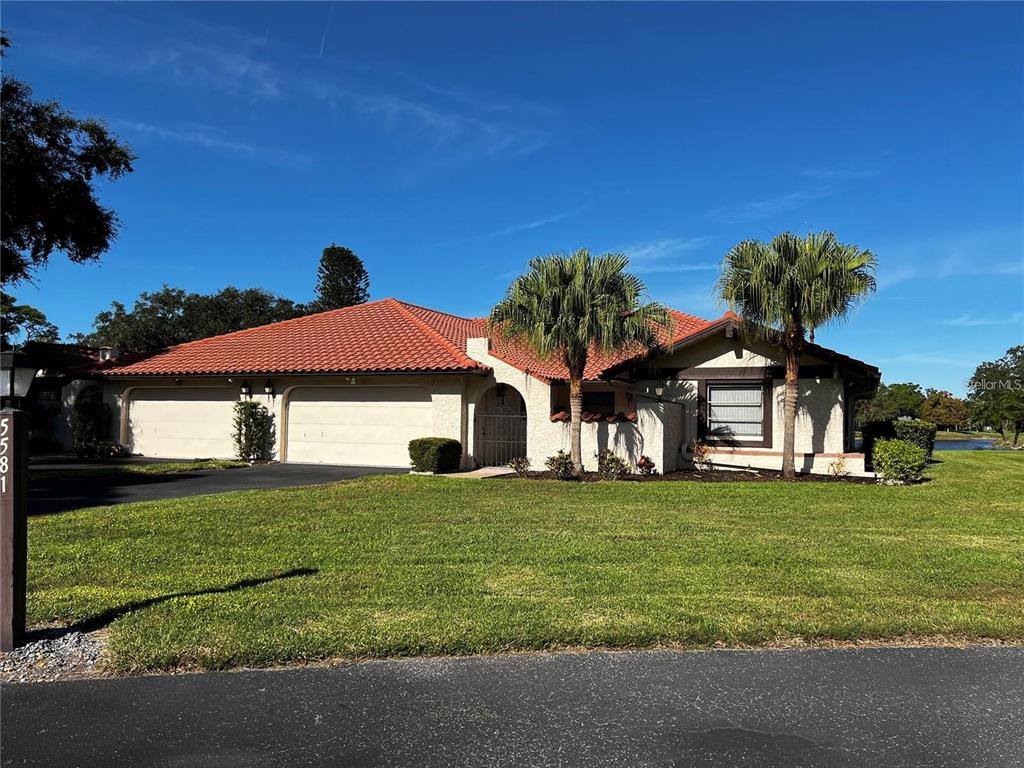 A single-story house with a red tile roof, two garage doors, and two palm trees — 5581 GOLF POINTE DRIVE, SARASOTA, FL