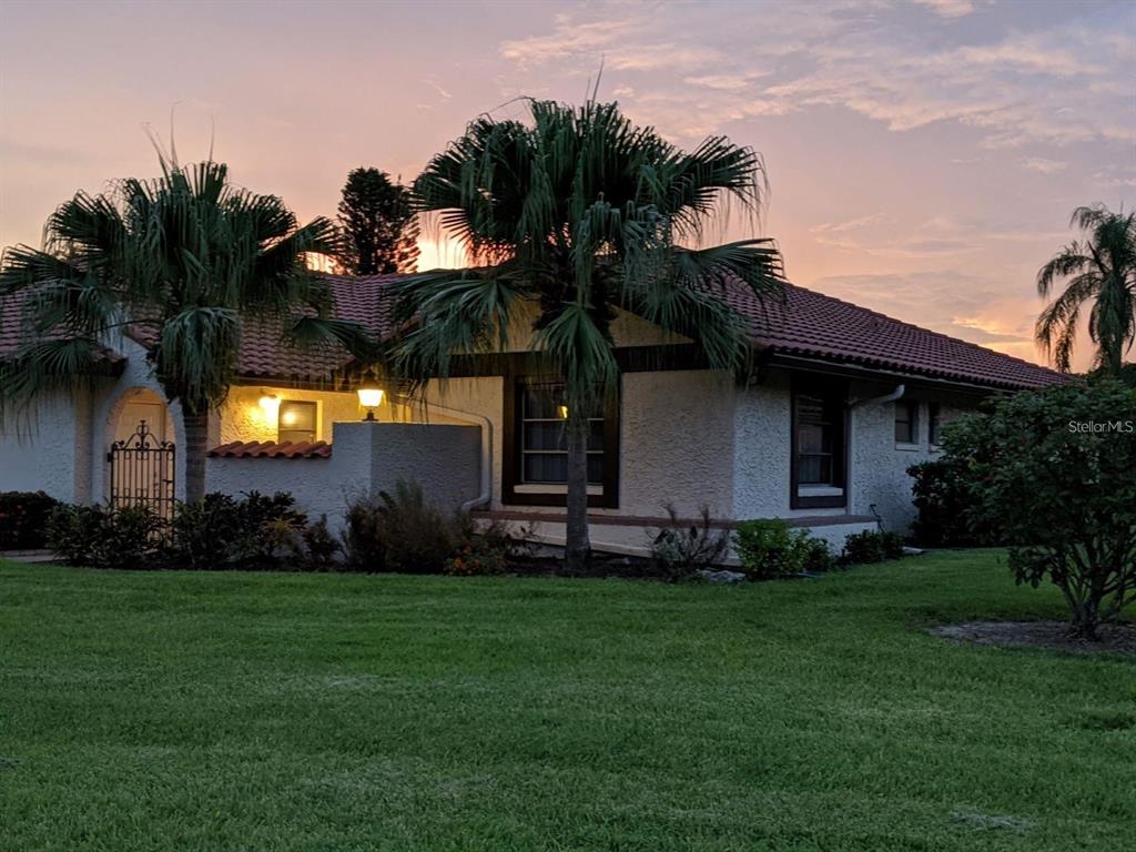 A single-story house with a tiled roof and palm trees at sunset — 5581 GOLF POINTE DRIVE, SARASOTA, FL