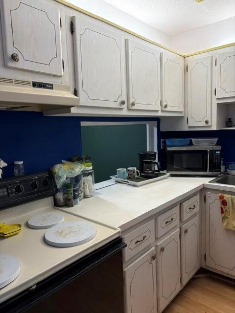 A kitchen features white wood-grain cabinets, a dark blue accent wall, and a microwave — 2640 Garden Drive S # 103, Lake Worth FL 33461, LAKE WORTH, FL