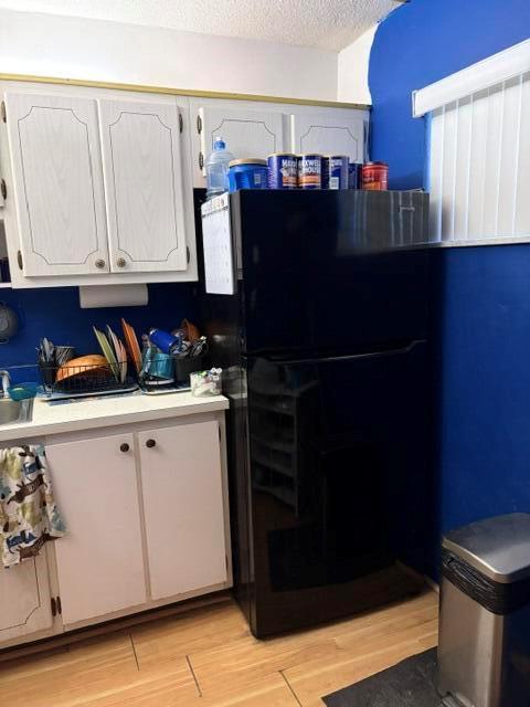 A kitchen features white cabinets, a black refrigerator, and blue walls — 2640 Garden Drive S # 103, Lake Worth FL 33461, LAKE WORTH, FL