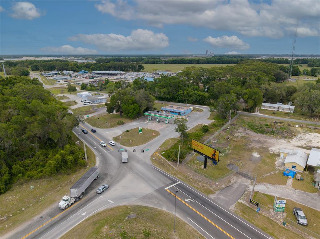 An aerial view shows a gas station at a rural intersection with a large billboard — 487 S US 301, SUMTERVILLE, FL