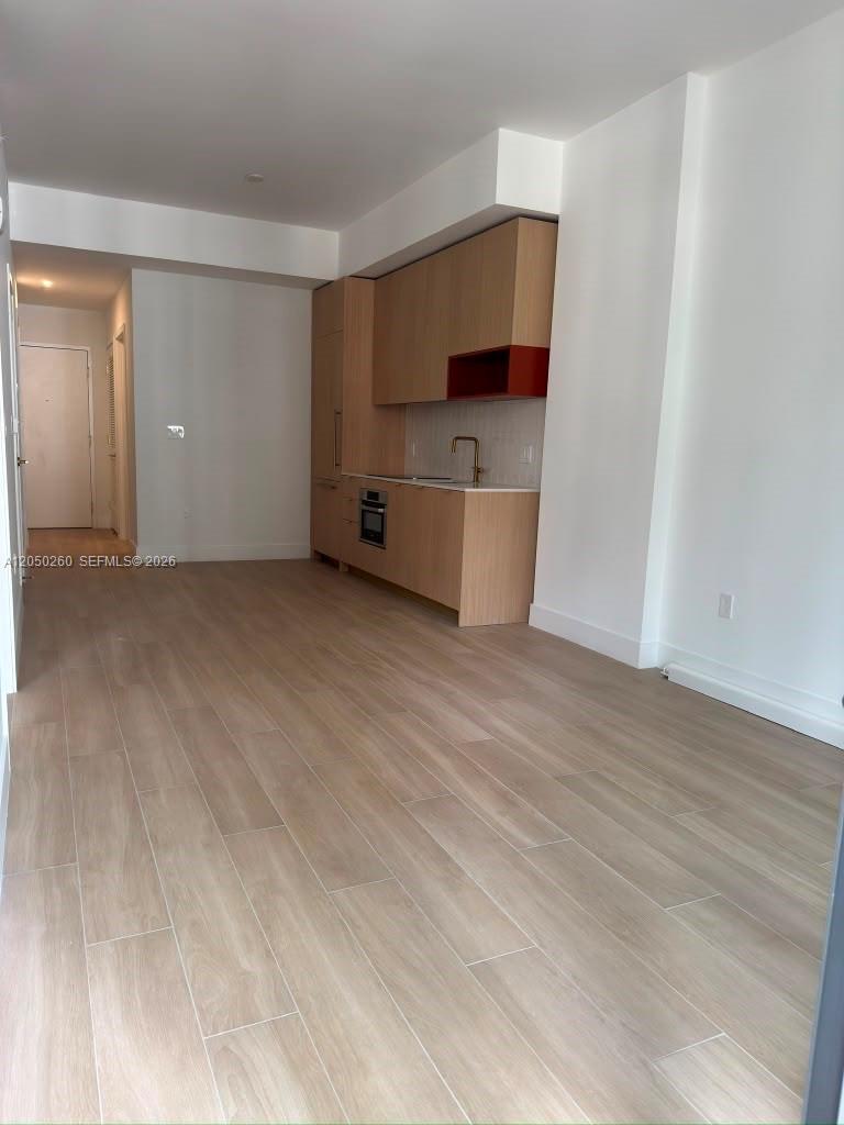 This kitchen features light wood cabinetry, a red open shelf, and light-colored wood-look flooring — 90 NE 32 ST # 206, Miami FL 33137, MIAMI, FL