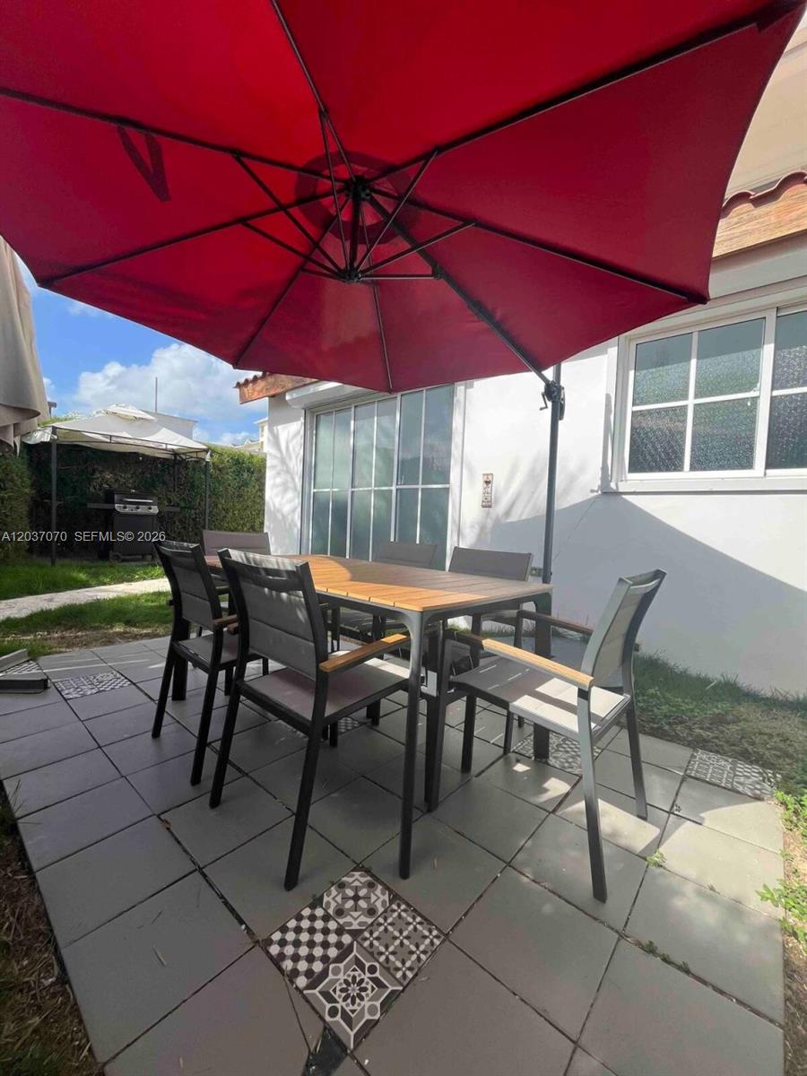 A patio features a dining set under a large red umbrella on a tiled floor — 0 Los corales # 0, FL, FL