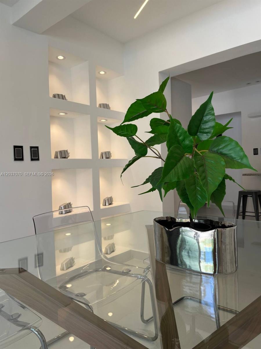 A dining area features a glass table, clear chairs, and a white wall with recessed shelving — 0 Los corales # 0, FL, FL