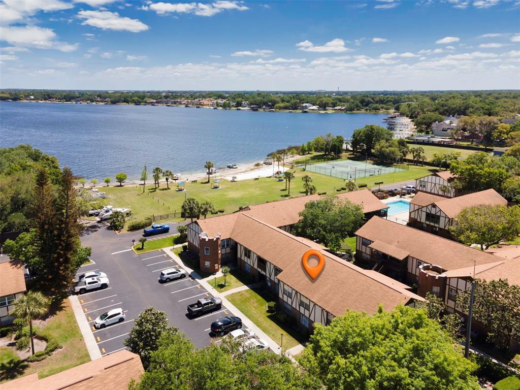 An aerial view shows a multi-story apartment complex with a parking lot and lakefront access — 5441 HANSEL AVENUE UNIT J15, ORLANDO, FL