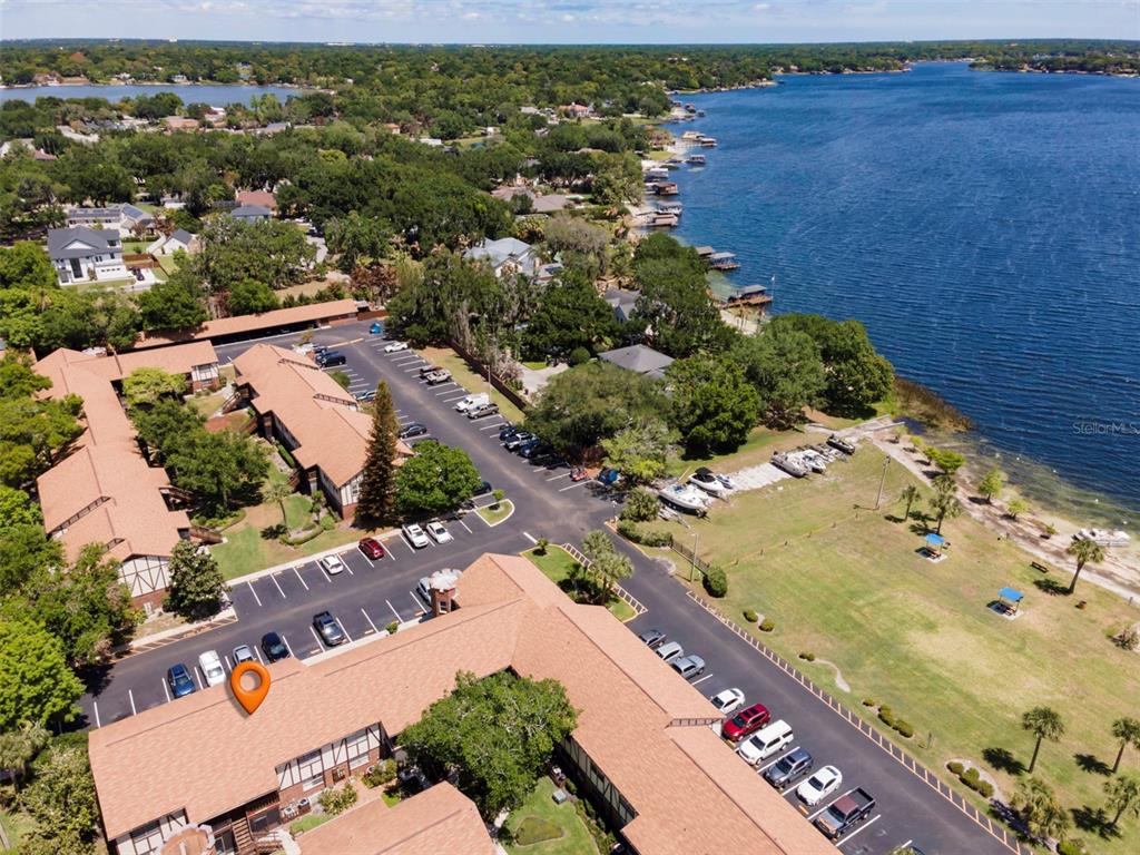 An aerial view shows a multi-unit residential complex with parking lots next to a lake — 5441 HANSEL AVENUE UNIT J15, ORLANDO, FL