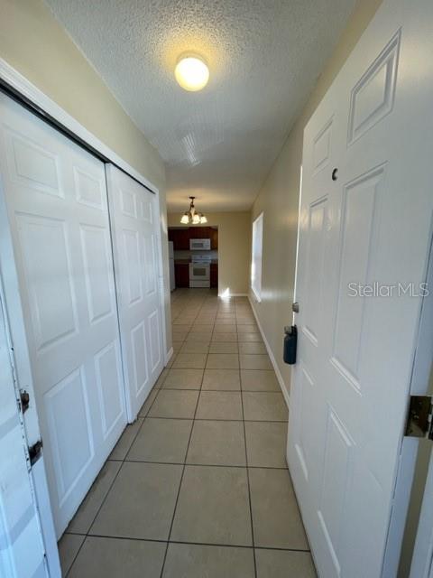 A tiled hallway leads from an entryway toward a kitchen with white cabinets — 1813 MICHIGAN AVENUE UNIT C, KISSIMMEE, FL
