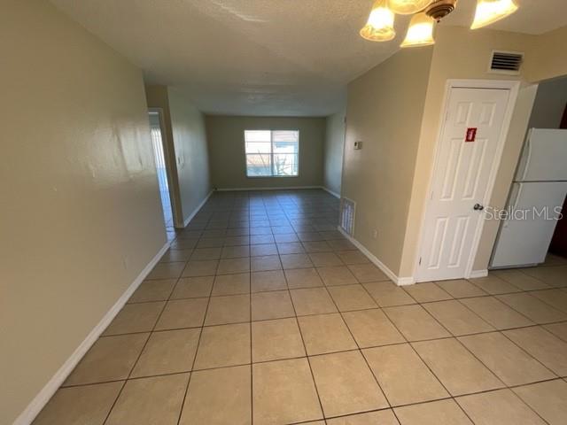 A tiled dining area leads to a living room with a window and white refrigerator — 1813 MICHIGAN AVENUE UNIT C, KISSIMMEE, FL