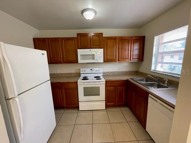 A kitchen with wood cabinets, white appliances, and light-colored tile flooring — 1813 MICHIGAN AVENUE UNIT C, KISSIMMEE, FL