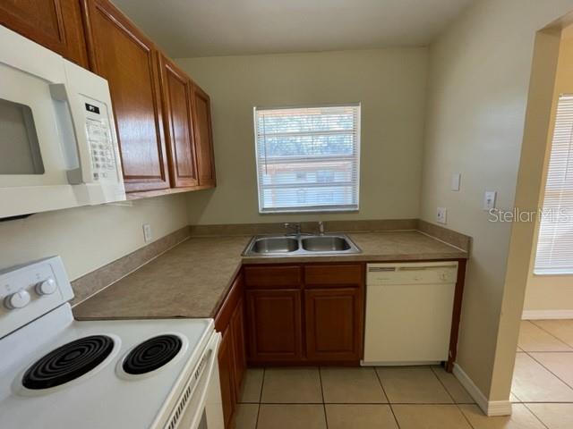 A kitchen features wood cabinets, a white dishwasher, a double sink, and a white stove — 1813 MICHIGAN AVENUE UNIT C, KISSIMMEE, FL