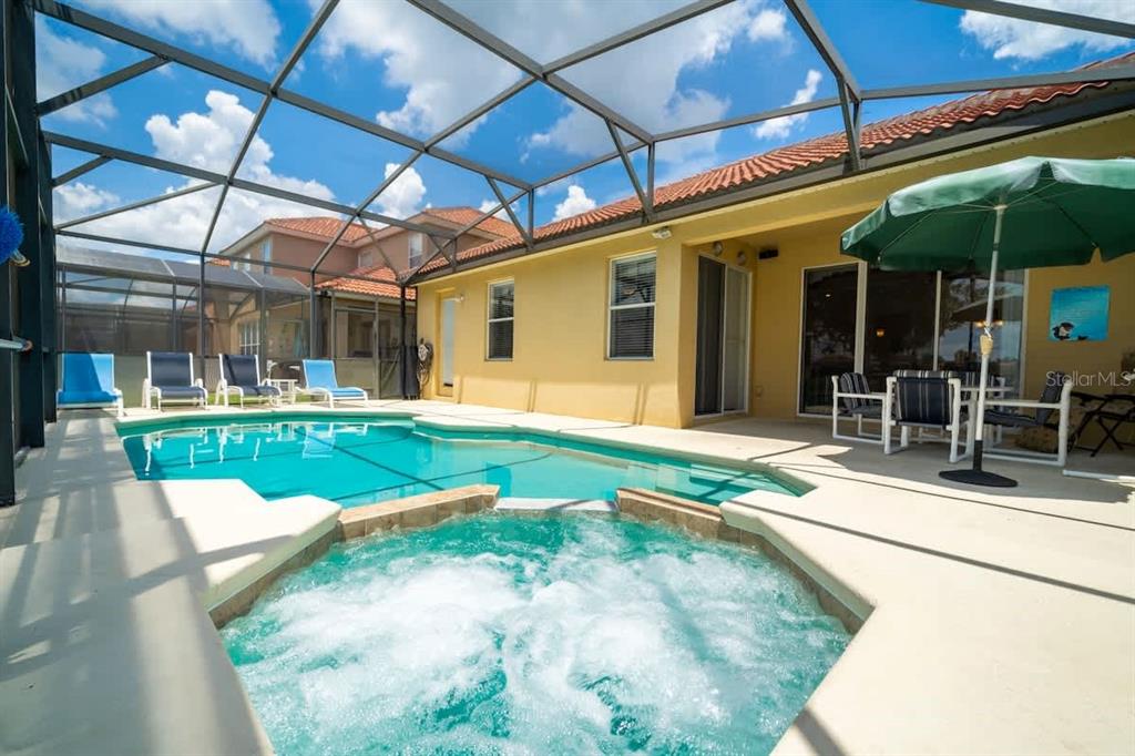 A swimming pool and hot tub are enclosed within a screened lanai behind a house — 950 MARCELLO BOULEVARD, KISSIMMEE, FL