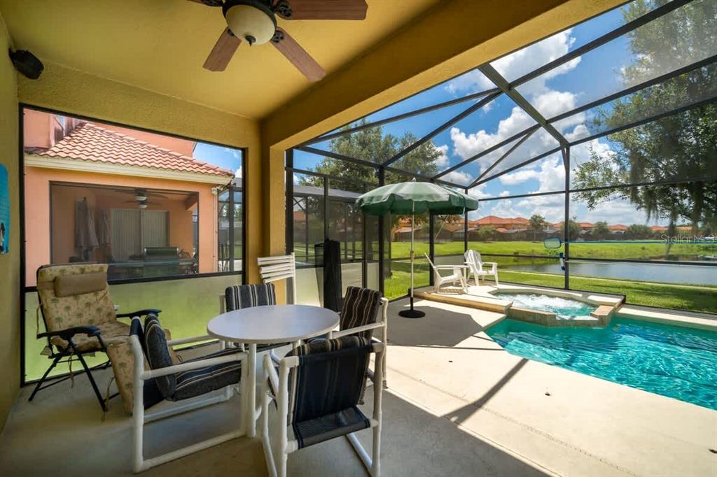 A covered patio features a dining set, lounge chair, and a screened-in pool and spa — 950 MARCELLO BOULEVARD, KISSIMMEE, FL
