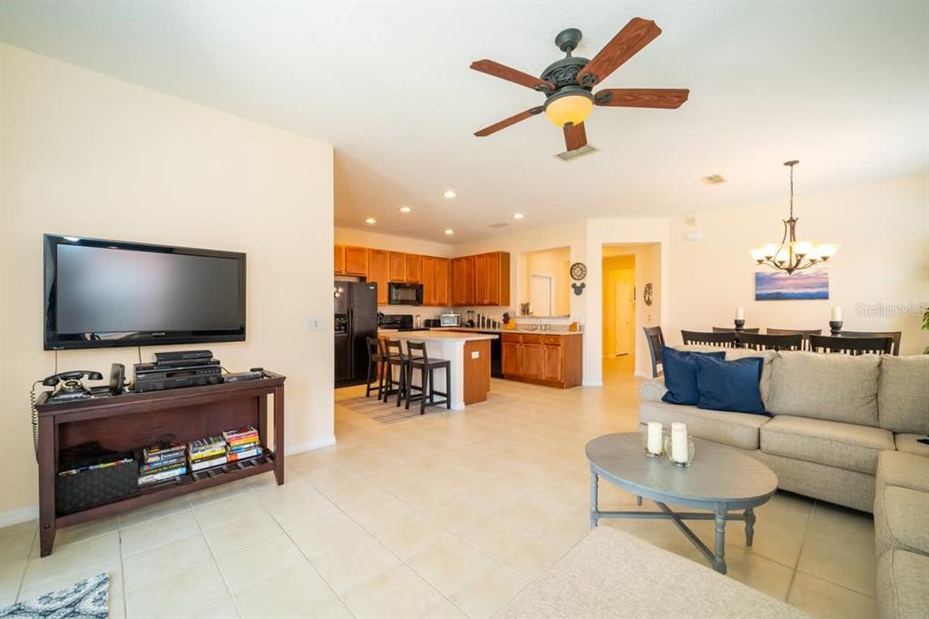 An open-concept living room and kitchen featuring tile flooring, wooden cabinets, and a ceiling fan — 950 MARCELLO BOULEVARD, KISSIMMEE, FL