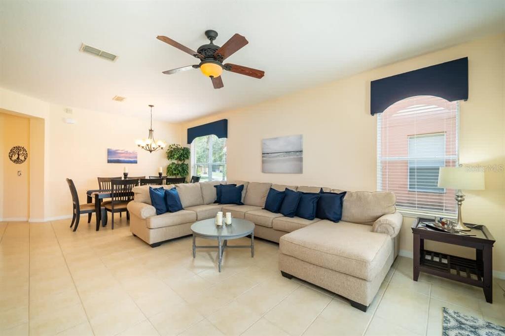 A living room features a beige sectional sofa, a round coffee table, and a dining area — 950 MARCELLO BOULEVARD, KISSIMMEE, FL