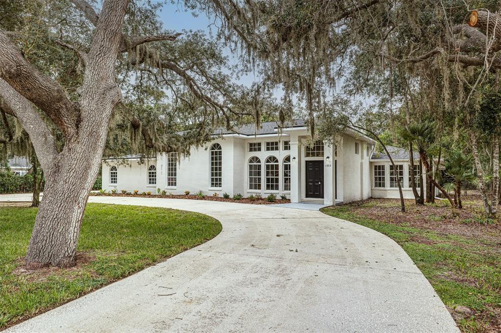 A white brick house with a curved driveway and large oak trees in the front yard — 1955 CAPPS ROAD, LAKE WALES, FL