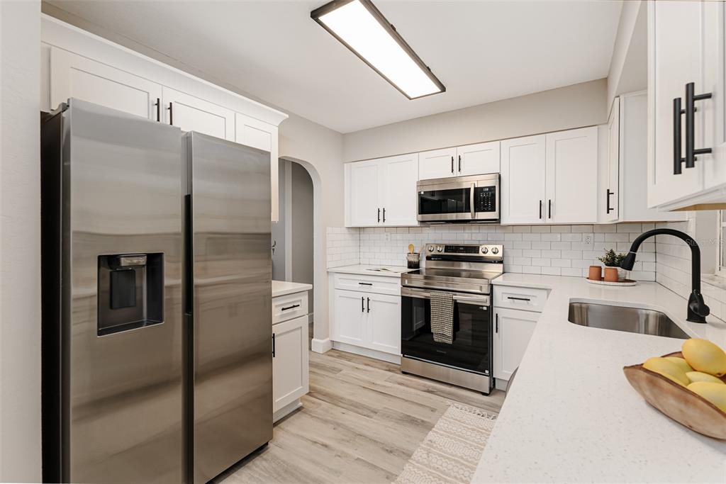 A modern kitchen features white cabinets, stainless steel appliances, and light-colored countertops — 1955 CAPPS ROAD, LAKE WALES, FL