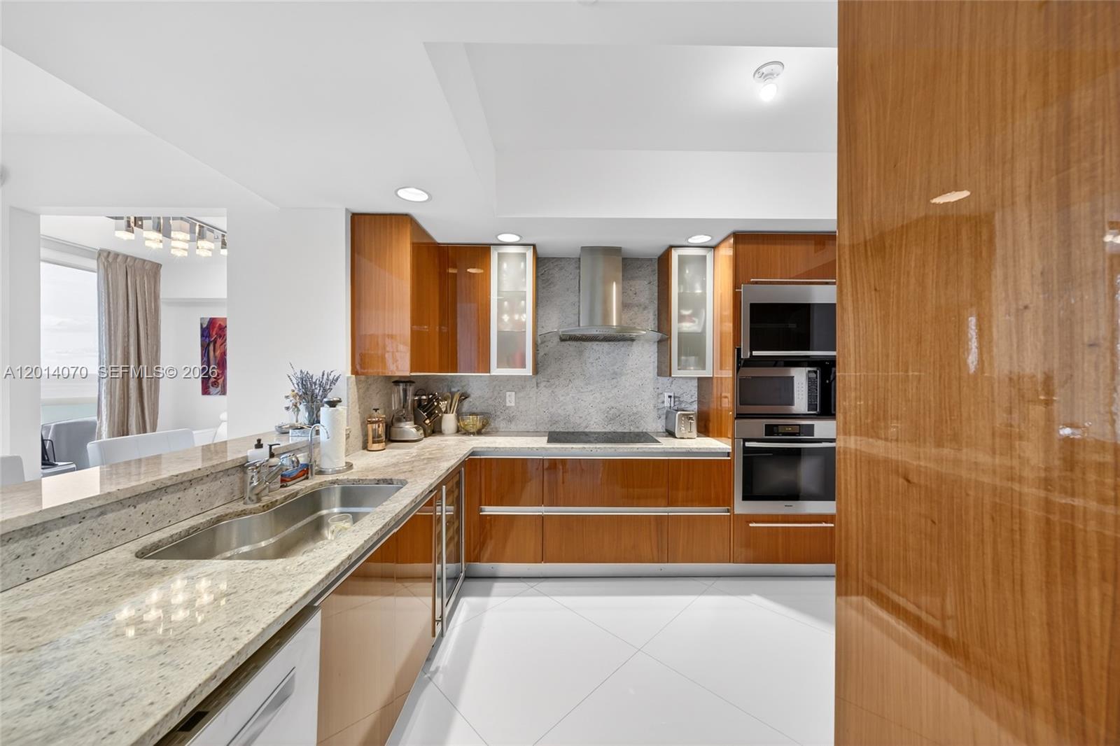 A modern kitchen features glossy wood cabinets, granite countertops, and stainless steel appliances — 2711 S Ocean Dr # 1901, Hollywood FL 33019, HOLLYWOOD, FL