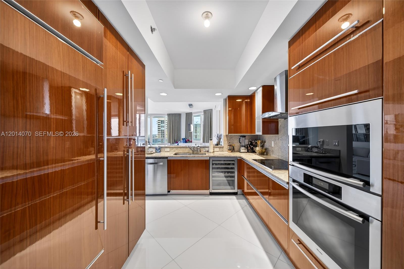 A modern kitchen features glossy wood cabinetry, stainless steel appliances, and white tile flooring — 2711 S Ocean Dr # 1901, Hollywood FL 33019, HOLLYWOOD, FL