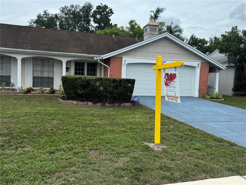 A single-story house with a brick facade, a two-car garage, and a yellow real estate sign — 3438 MOOG ROAD, HOLIDAY, FL