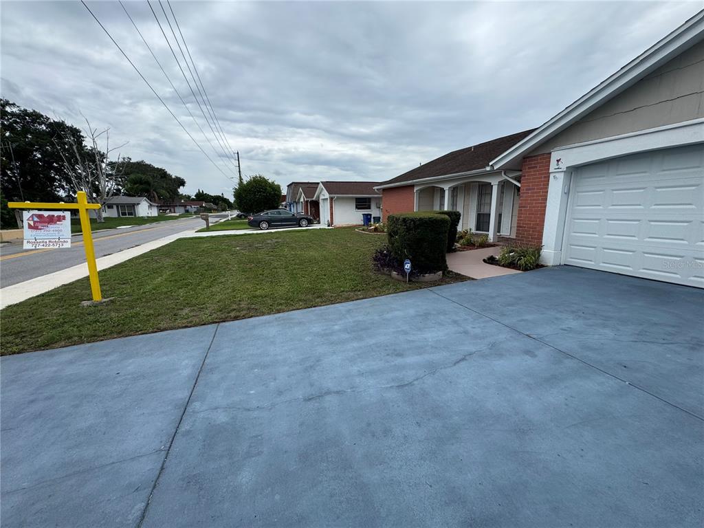 A residential street view shows a house with a blue driveway and a front lawn — 3438 MOOG ROAD, HOLIDAY, FL