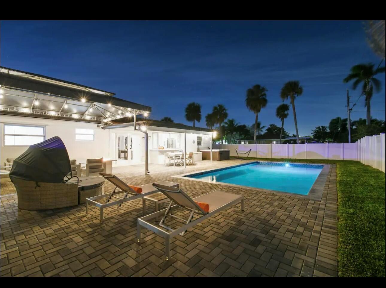 A backyard patio features a swimming pool, lounge chairs, a covered seating area, and palm trees — 5040 NE 22nd Avenue, Lighthouse Point FL 33064, LIGHTHOUSE POINT, FL