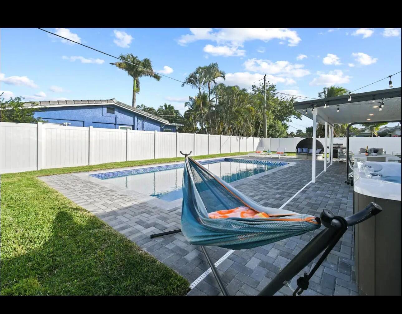 A backyard features a rectangular swimming pool, a hammock, a hot tub, and white fencing — 5040 NE 22nd Avenue, Lighthouse Point FL 33064, LIGHTHOUSE POINT, FL