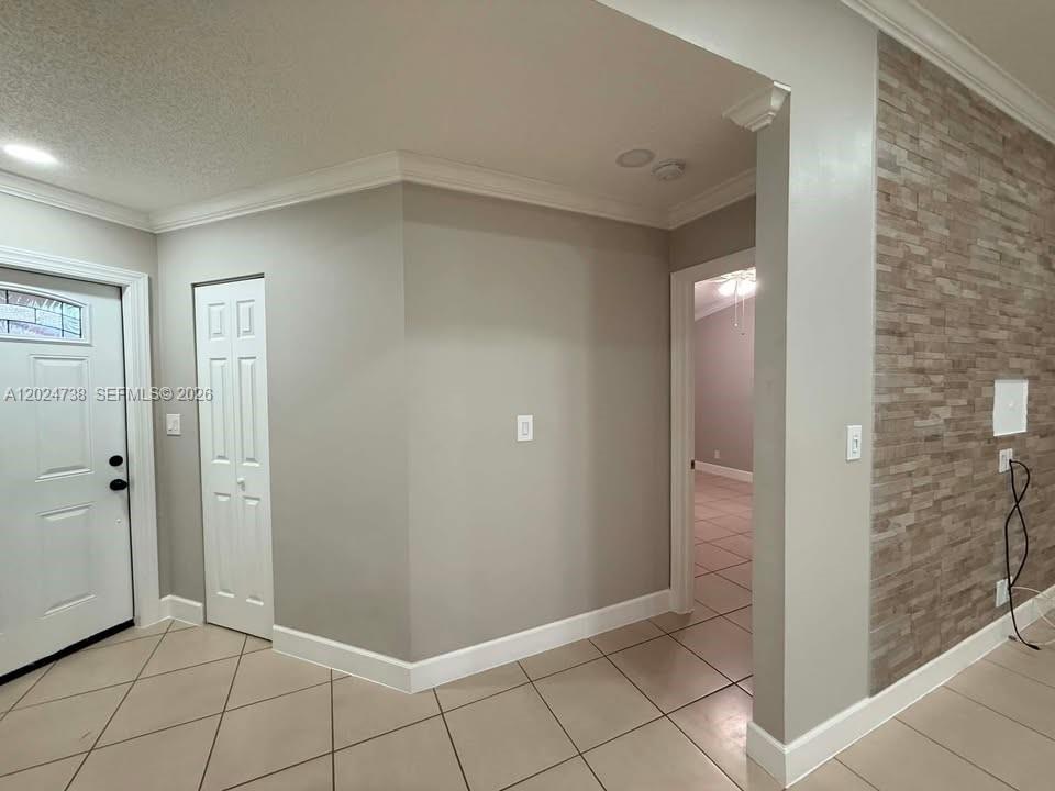 An entryway with tile flooring, a white door, a closet, and a stone accent wall — 6449 NW 171st St # 0, Hialeah FL 33015, HIALEAH, FL