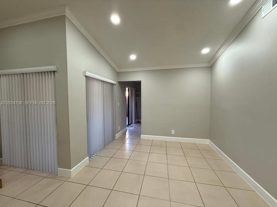 An empty room features light-colored tile flooring, neutral walls, recessed lighting, and vertical blinds — 6449 NW 171st St # 0, Hialeah FL 33015, HIALEAH, FL