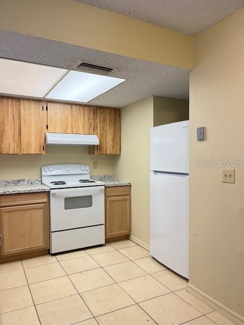 A kitchen with light wood cabinets, a white stove, and a white refrigerator on tiled floors — 821 MARGARET STREET UNIT A, DELAND, FL