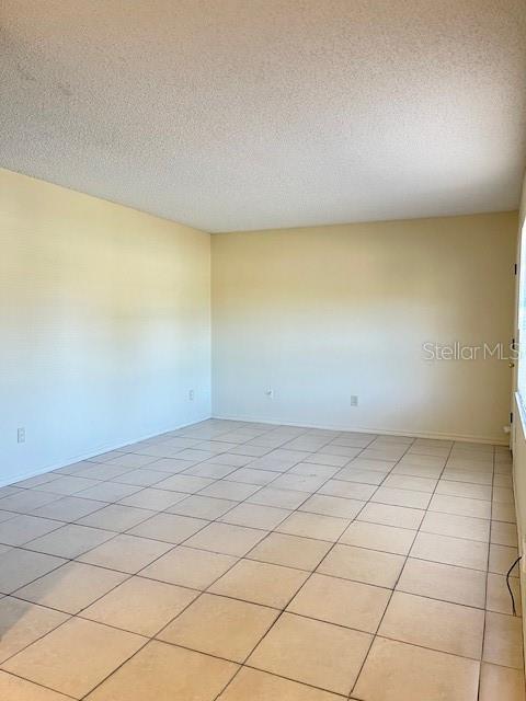 An empty room features light-colored walls, a textured ceiling, and beige floor tiles — 821 MARGARET STREET UNIT A, DELAND, FL
