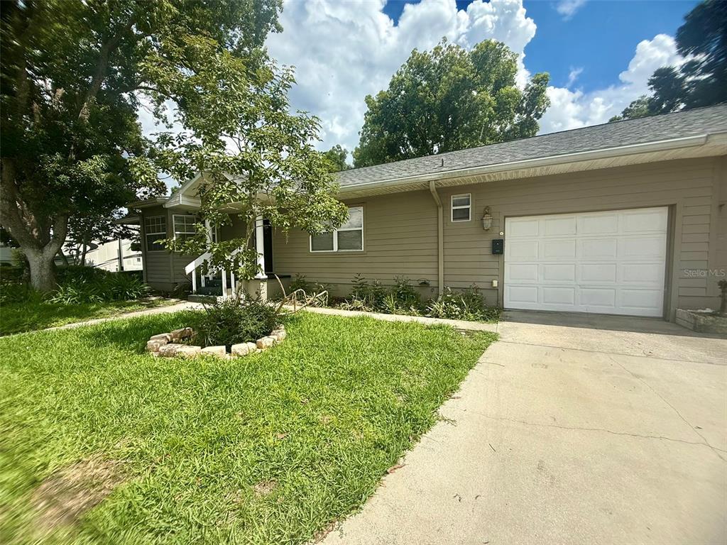 A single-story house with tan siding, a front porch, and a concrete walkway — 702 AVENUE H NE, WINTER HAVEN, FL