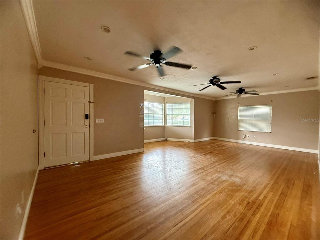A single-story house with tan siding, a white garage door, and a small front porch — 702 AVENUE H NE, WINTER HAVEN, FL