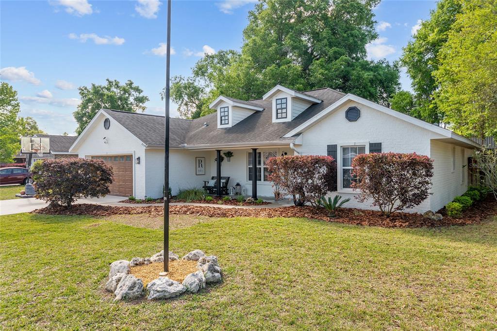 A white brick house with a dark shingled roof, dormer windows, and a front yard — 25175 SW 20TH AVENUE, NEWBERRY, FL