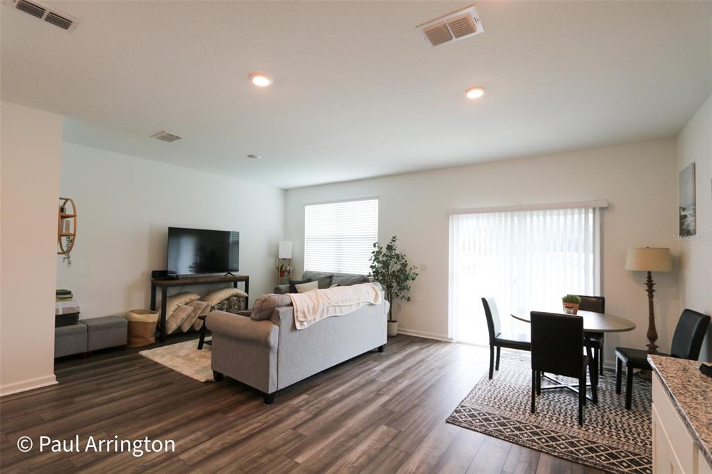 An open-concept living and dining area features wood-look flooring, recessed lighting, and sliding glass doors — 6371 KAY MORGAN LANE, GIBSONTON, FL
