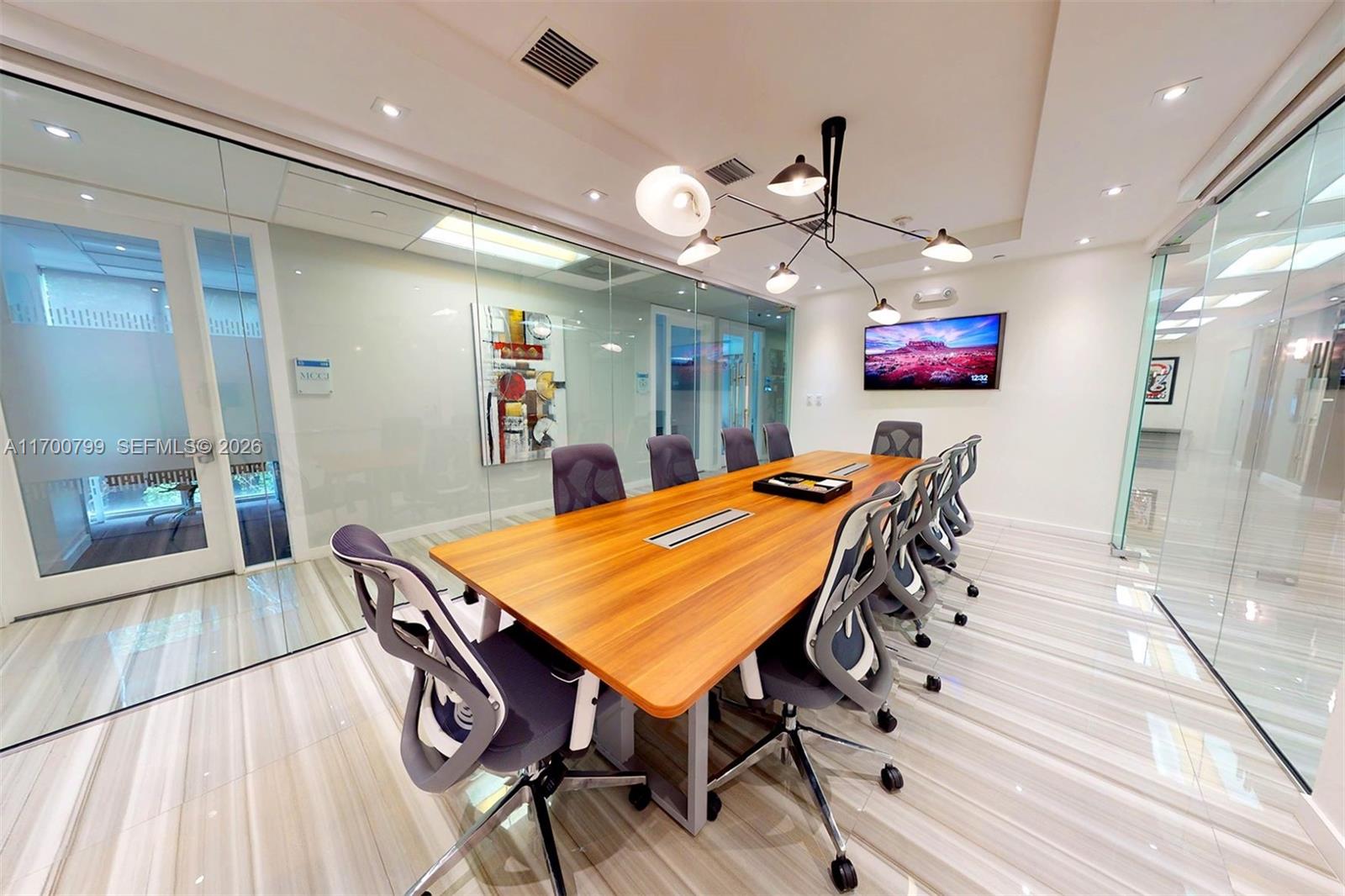 A modern conference room features a long wooden table, ergonomic chairs, and glass-walled partitions — 150 SE 2nd AVE # 332, Miami FL 33131, MIAMI, FL