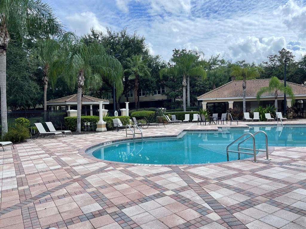 A swimming pool with lounge chairs on a paved deck surrounded by palm trees — 7057 CADIZ BOULEVARD, ORLANDO, FL