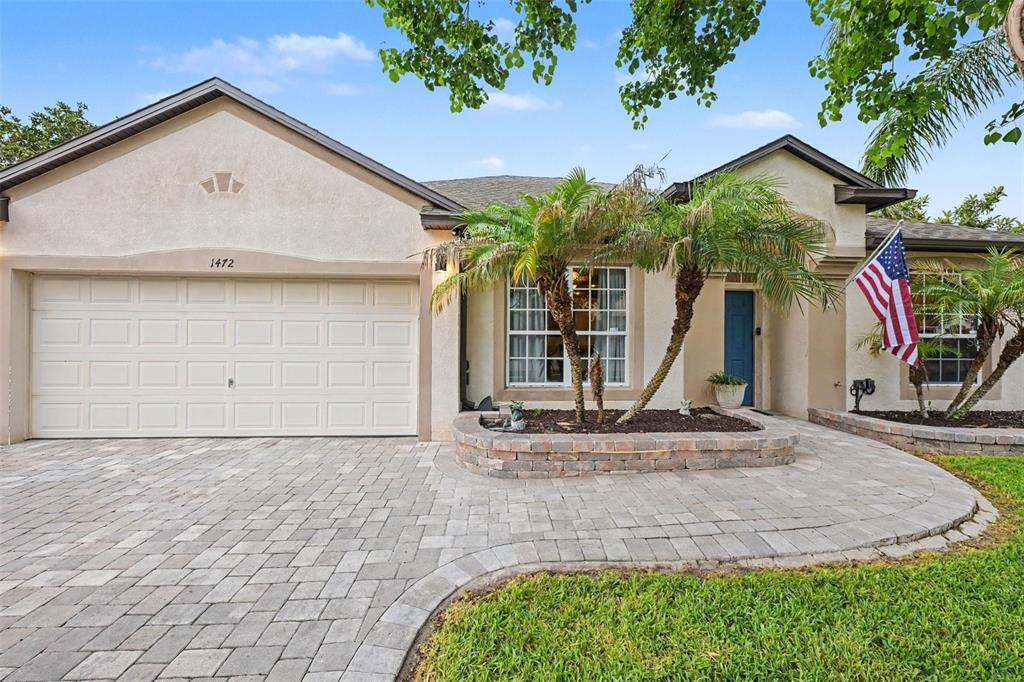 A living room features wood-look flooring, a white front door, a green sofa, and shelving — 1472 KODAK DRIVE, TITUSVILLE, FL
