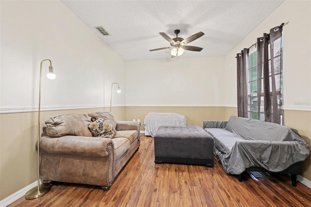 A living room with wood flooring, a green sofa, and an arched doorway to a kitchen — 1472 KODAK DRIVE, TITUSVILLE, FL