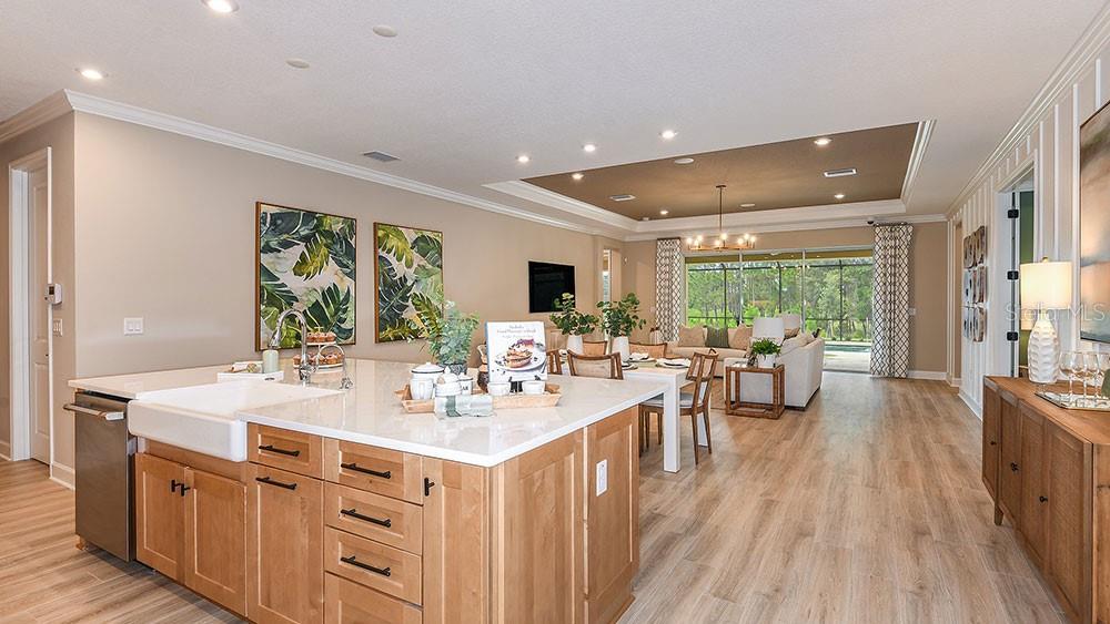 A kitchen island with a farmhouse sink faces an open-concept living and dining area — 11283 MANOR HOUSE LANE, ODESSA, FL