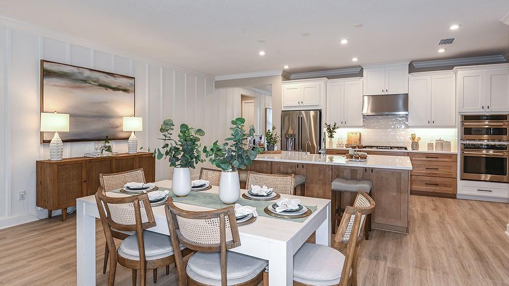 A dining area with a white table and chairs sits adjacent to a modern kitchen — 11283 MANOR HOUSE LANE, ODESSA, FL