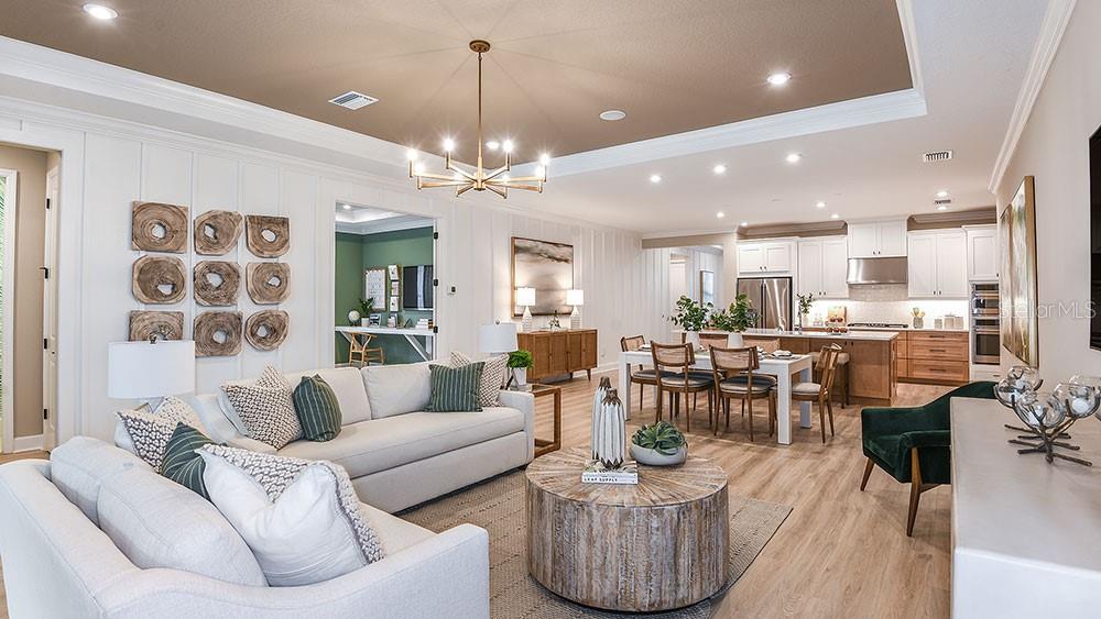 An open-concept living room and kitchen featuring light wood floors, white cabinetry, and neutral furniture — 11283 MANOR HOUSE LANE, ODESSA, FL