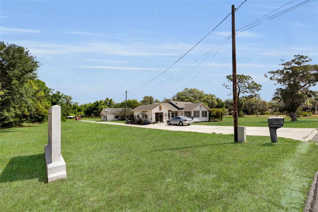 A single-story house sits on a large grassy lot with a paved driveway and mailbox — 5223 EAGLES NEST ROAD, FRUITLAND PARK, FL