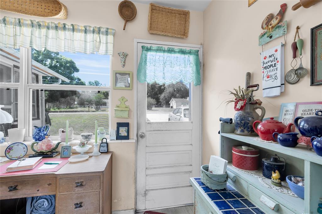 A country-style kitchen features a wooden desk, a white door, and open shelving with decor — 5223 EAGLES NEST ROAD, FRUITLAND PARK, FL