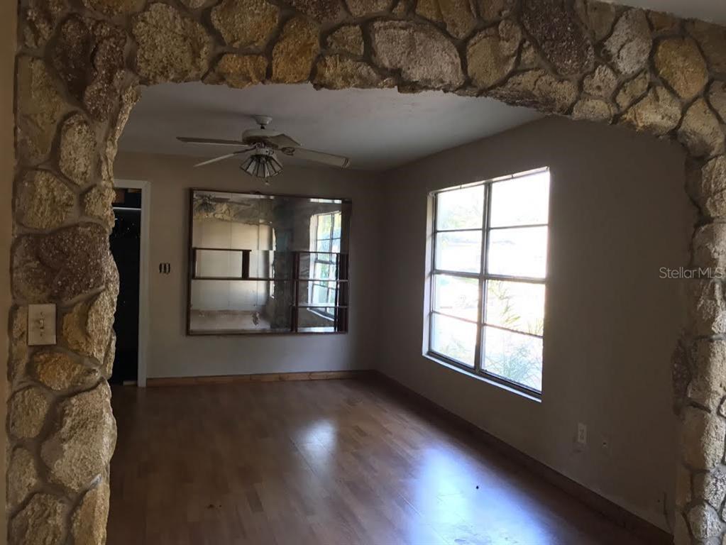 An interior room features light wood flooring, beige walls, and a prominent stone-faced arched entryway — 229 S CANDLER AVENUE, ORLANDO, FL