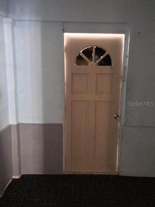 A hallway with wood-look laminate flooring leads to an open doorway showing a carpeted room — 229 S CANDLER AVENUE, ORLANDO, FL
